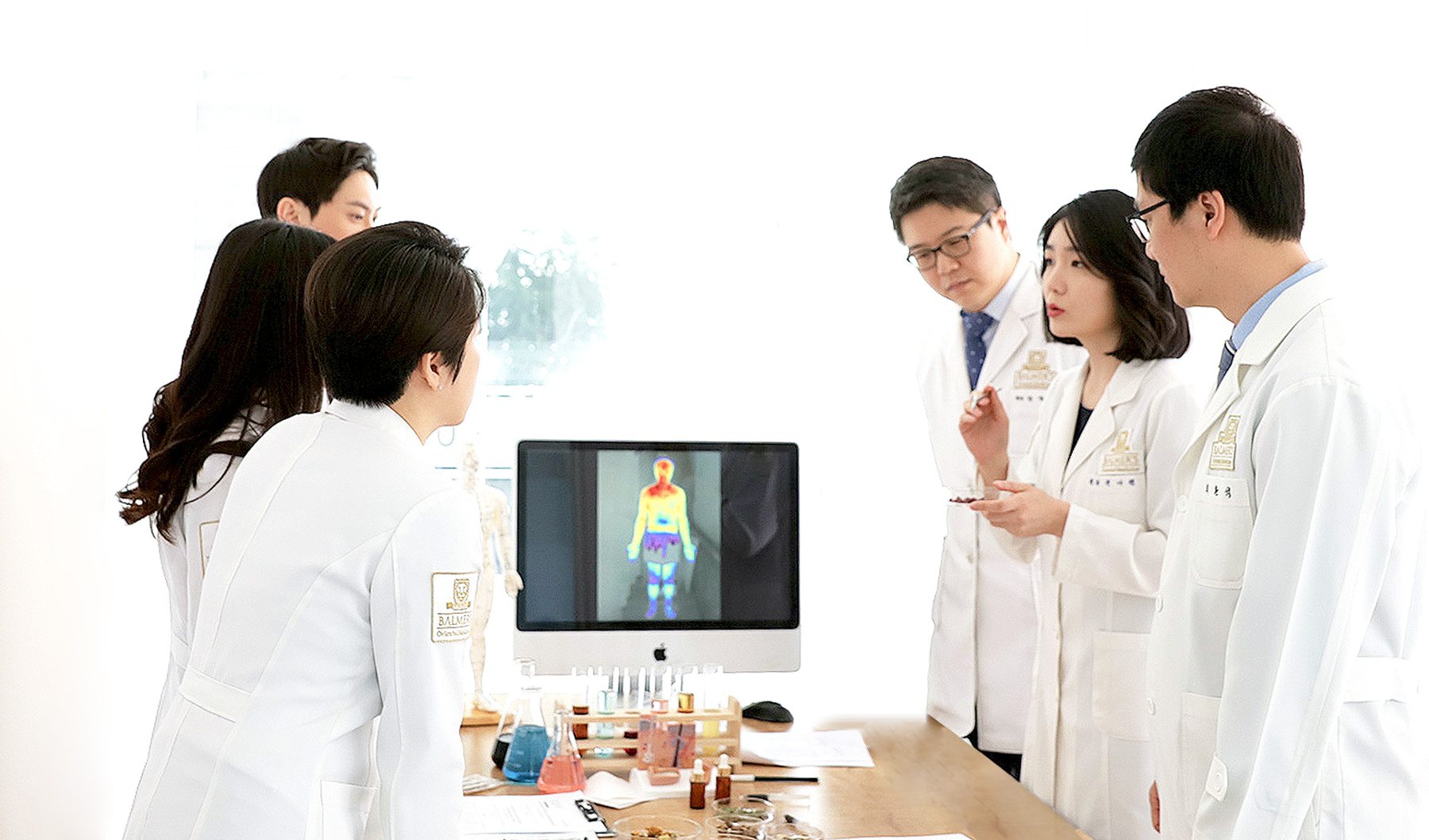 체열 촬영 모니터와 약재 책상을 둘러싼 발머스한의원 한의사들